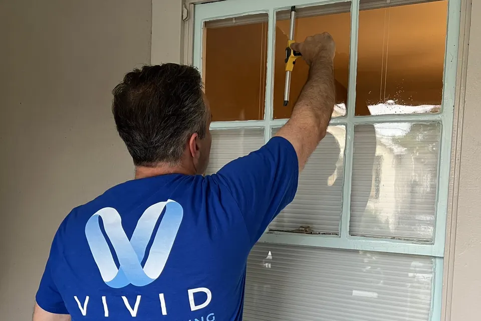 Darin of Vivid Window Cleaning cleaning a residential window with a squeegee